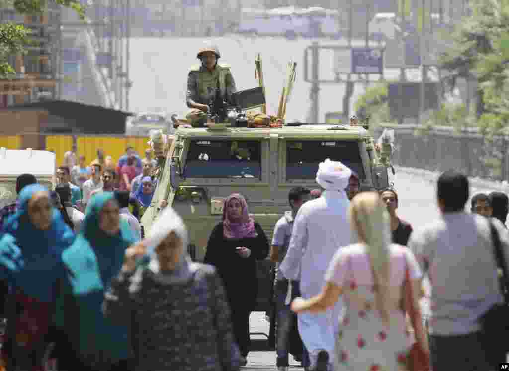 An army soldier stands alert over an armored vehicle near Nahda Square, where supporters of Egypt's ousted President Mohamed Morsi have installed their camp, Cairo, August 12, 2013.