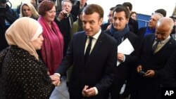 French President Emmanuel Macron shakes hands with a resident next to French Minister of Public Action and Accounts Gerald Darmanin, second right, during a visit to Tourcoing, Nov. 14, 2017.
