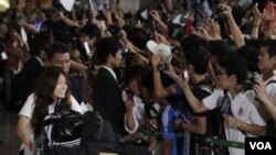Kapten tim nasional sepakbola putri Jepang Homare Sawa (kiri) berjalan melewati penggemar yang menyambut timnya di bandara internasional Narita, Selasa (19/7).