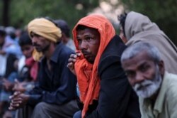 Daily wage workers and homeless people wait for food outside a government-run night shelter during a 21-day nationwide lockdown, in New Delhi, March 25, 2020.