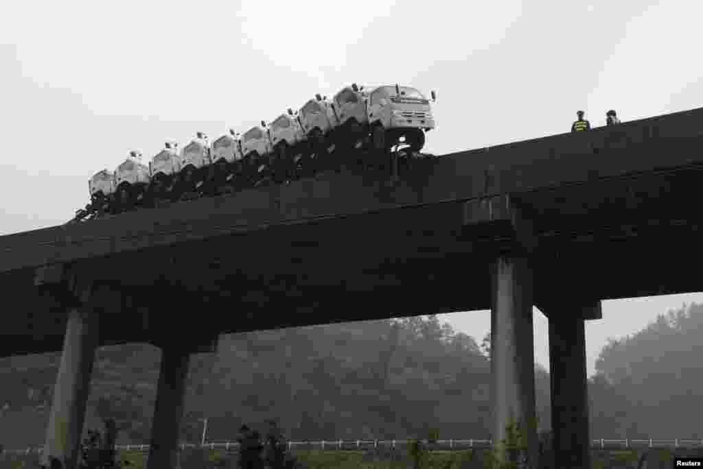 A trailer loaded with trucks hangs on the edge of the guardrail on a bridge in Kaili, Guizhou province, China, Oct. 21, 2013. According to local media, the trailer hanged on the edge of the bridge after the driver lost control of the vehicle. No injury was reported.