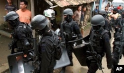 Para anggota Densus 88 membawa perlengkapan dan senjata mereka setelah melakukan penggerebekan di rumah yang ditempati oleh militan di Kabupaten Bandung. (Foto: AP)