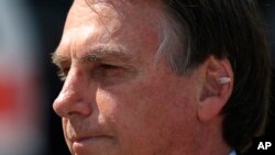 With a band aid on his ear, Brazil's President Jair Bolsonaro attends a military ceremony in honor of Sailor Day, in Brasilia, Brazil, Friday, Dec. 13, 2019.
