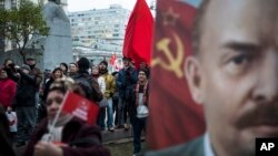 Communist Party supporters stand next to a monument to Karl Marx, left, and hold Soviet flags and portraits of Soviet founder Vladimir Lenin, right, during a demonstration marking the 100th anniversary of the 1917 Bolshevik Revolution in Moscow, Russia, Nov. 7, 2017.