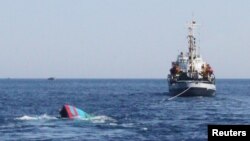 A Vietnamese sinking boat (L) which was rammed and then sunk by Chinese vessels near disputed Paracels Islands, is seen near a Marine Guard ship (R) at Ly Son island of Vietnam's central Quang Ngai province May 29, 2014.