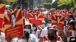 ក្រុម​បាតុករ​ប្រឆាំង​នឹង​រដ្ឋប្រហារ​យោធា​នាំ​គ្នា​កាន់​បដា​មួយ​ដែល​មាន​រូប​របស់​អ្នកស្រី Aung San Suu Kyi ខណៈ​ដែល​ពួកគេ​​ប្រមូលផ្ដុំ​គ្នា​នៅ​ខាង​ក្រៅ​ការិយាល័យ​អង្គការ​សហប្រជាជាតិ​ក្នុង​ទីក្រុង​រ៉ង់ហ្គូន ប្រទេស​មីយ៉ាន់ម៉ា ថ្ងៃទី១៤ ខែកុម្ភៈ ឆ្នាំ២០២១។ 