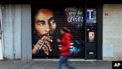A woman walks past a mural depicting reggae music icon Bob Marley painted on the rolling shutter of a Tobacco shop in Rome, Thursday, Nov. 28, 2018. (AP Photo/Gregorio Borgia)