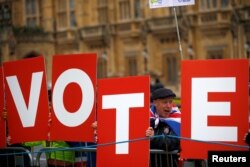 Anti-Brexit demonstrators hold placards outside the Houses of Parliament in London, Britain, Dec. 10, 2018.