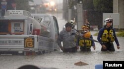 បុរស​ម្នាក់​ត្រូវ​បាន​ប៉ូលិស​សង្រ្គោះ​បន្ទាប់ពី​រថយន្ត​លោក​ត្រូវ​ជាប់​ក្នុង​ទឹកជំនន់​ក្នុង​ទីក្រុង​Omuta ប្រទេស​ជប៉ុនកាលពី​ថ្ងៃទី​០៧ ខែកក្កដា ឆ្នាំ២០២០។