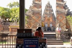 Seorang perempuan menunggu para wisatawan di Pura Puseh, Desa Batuan, Gianyar, Bali, 5 Februari 2020. (Foto: Reuters)
