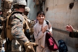 In this photo provided by the U.S. Marine Corps, a boy is processed through an Evacuee Control Checkpoint during an evacuation at Hamid Karzai International Airport, in Kabul, Afghanistan, Wednesday, Aug. 18, 2021.