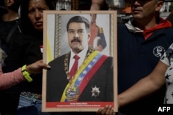 Supporters of Venezuelan President Nicolas Maduro hold a portrait of him in a ceremony to swear him in symbolically in front of the National Assembly building during a rally around the city in Caracas, Venezuela on Jan. 7, 2019.