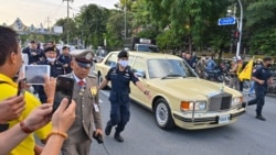 Police escort the limousine carrying Thailand's Queen Suthida and Prince Dipangkorn Rasmijoti as royalist supporters take photos of the the royal motorcade in Bangkok on October 14, 2020. (Photo by Mladen ANTONOV / AFP)