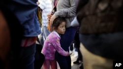 FILE - Nicole Hernandez, of the Mexican state of Guerrero, holds on to her mother as they wait with other families to request political asylum in the United States, across the border in Tijuana, Mexico, June 13, 2018.