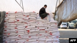 A Palestinian worker rests on a stack of flour at an aid distribution centre in the southern Gaza Strip city of Khan Yunis on December 3, 2024.