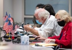 FILE - A man checks the ID of a voter before giving them a ballot at an early voting location in Fairfax, Virginia on Sept. 18, 2020.