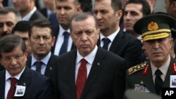 Presiden Turki Recep Tayyip Erdogan (tengah) dan PM Ahmet Davutoglu menghadiri pemakaman Seckin Cil, seorang dari 6 tentara Turki yang tewas dalam pemboman oleh militan Kurdi (PKK) di Ankara pada hari Rabu (18/2).