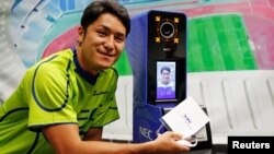 NEC Green Rockets' rugby player Teruya Goto poses with the face recognition system for Tokyo 2020 Olympics and Paralympics, which is developed by NEC corp, during its demonstration in Tokyo, Japan, Aug. 7, 2018. 