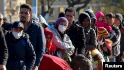 Migrants queue on a bridge crossing the border river Inn at the German-Austrian frontier between Braunau and Simbach am Inn near Passau, Germany, Nov. 1, 2015. Chancellor Angela Merkel failed to resolve differences within her ruling coalition on dealing with the crisis over a huge refugee influx, leaving open a row that has dented her conservatives' popularity. 