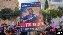 Para pemrotes Israel, mengenakan masker di tengah pandemi Covid-19 sambil memegang poster PM Benjamin Netanyahu di luar kediaman resminya di Yerusalem, 24 Juli 2020.