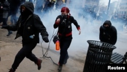 Para demonstran berlarian setelah polisi mempergunakan gas airmata dan granat kejut untuk membubarkan protes anti Trump di Washington DC, hari Jumat (20/1).