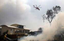 A fire bombing helicopter works to contain a bushfire along Old Bar road in Old Bar, New South Wales, Australia, Nov. 9, 2019. (AAP Image/Shane Chalker/via Reuters)