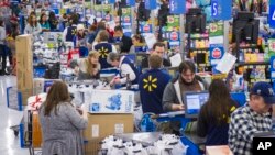 FILE - Sales clerks ring up customers at a Walmart store in Bentonville, Arkansas, Nov. 27, 2014. New data shows that, in a trend reversal, Americans enjoyed a median household income hike of 5.2 percent in 2015.