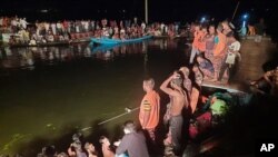 방글라데시 브라만바리아 지역의 대형 못에서 선박 사고가 일어난 현장에 사람들이 모여 수색 작업을 지켜보고 있다. 