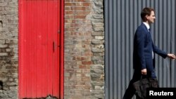 FILE - A man passes a red door and corrugated iron in central London, July 2, 2014. Asylum seekers in the northern English town of Middlesbrough are suffering abuse because they have been housed in properties that almost all have red front doors, making them easy targets for racists.