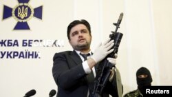 Markian Lubkivskyi, adviser of Ukraine's Security Service (SBU), shows a Kalashnikov automatic rifle with grenade launcher seized from a man identified by SBU as one of two Russian servicemen recently detained by Ukrainian forces, in Kyiv, May 21, 2015.