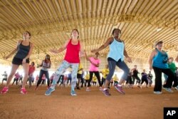 FILE - Fitness enthusiasts run through dance exercises as they work out at Tropical Park in Miami, Florida.