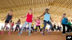 FILE - Fitness enthusiasts run through dance exercises as they work out at Tropical Park in Miami, Florida, July 25, 2015.