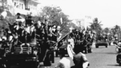 Flag-waving and jubilating Red Khmer soldiers enter the city of Phnom Penh on their trucks, April 17, 1975, when this Cambodian capital surrendered to the Khmer Rouge. Civilians pass the truck convoy on their motor scooters. (AP Photo)