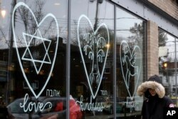 A woman walks past the window of a Starbucks in the Squirrel Hill neighborhood of Pittsburgh, Nov. 20, 2018. In the wake of the Tree of Life massacre, Squirrel Hill residents aren't shying away from celebrating Thanksgiving. They’re welcoming it.