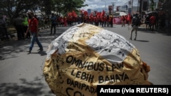 Tulisan "omnibus law lebih berbahaya dari COVID" tampak di tengah demo buruh memprotes Undang-Undang Cipta Kerja, di Bandung, Jawa Barat, Selasa, 6 Oktober 2020. (Foto: Antara via Reuters)