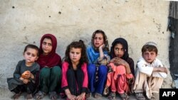 FILE - Children sit in front of a house at Deh Qubad village in Maiwand district of Kandahar province, Afghanistan, Sept. 27, 2020. 