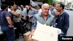 FILE - Displaced Syrians collect rations provided by the World Food Program in front of a distribution center in Damascus, Oct. 19, 2014.