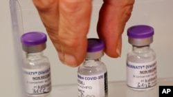 A health worker takes a dose of the Pfizer-BioNTech COVID-19 vaccine at the Rene-Muret hospital in Servan near Paris, Dec. 27, 2020. 