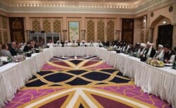 FILE - A handout photo released by the official Qatar's Ministry of Foreign Affairs, Feb. 26, 2019, shows Qatari officials, center, taking part in meeting between the U.S. delegation, left, and the Taliban delegation in Doha.