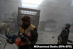 SYRIA -- White helmet volunteer carries an injured boy to an ambulance after bombing, in the rebel-held Douma, Eastern Ghouta, February 23, 2018