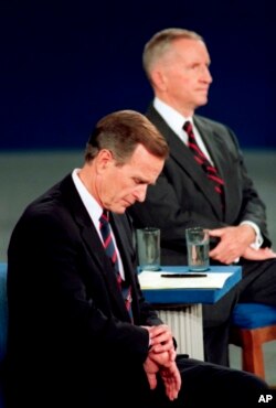 FILE - President George H.W. Bush checks his watch during the 1992 presidential campaign debate with Independent Ross Perot and Democrat Bill Clinton, not shown. Presidential candidates and their running mates often find that campaign debates turn on unpl