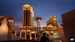 A man takes pictures of Caesars Palace hotel and casino, in Las Vegas.