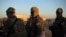FILE - Fighters of Syrian Democratic Forces (SDF) are seen standing near the village of Baghuz, Deir al-Zour province, Syria, March 1, 2019.