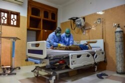 Karyawan rumah sakit mengenakan kacamata dan masker pelindung memeriksa seorang mahasiswa Aceh yang baru kembali dari China di fasilitas Karantina di sebuah rumah sakit di Banda Aceh, 29 Januari 2020. (Foto: AFP)