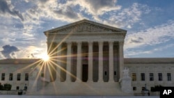 The sun flares in the camera lens as it rises behind the U.S. Supreme Court building in Washington, June 25, 2017.