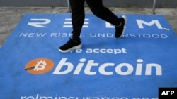 Un homme passe devant une bannière avec le logo du bitcoin pendant la conférence sur les crypto-monnaies Bitcoin 2021 Convention au Mana Convention Center à Miami, en Floride, le 4 juin 2021.