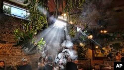 FILE - This Nov. 13, 2019, photo shows patrons smoking marijuana at Lowell's Original Cannabis Cafe, a legal marijuana establishment, in Los Angeles. A divided House panel has endorsed a proposal to decriminalize and tax marijuana at the federal level.