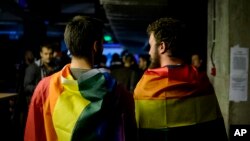 Two men draped in rainbow flags are seen in a nightclub in Bucharest, Romania, Oct. 7, 2018, following a referendum on marriage which was voided due to low voter turnout.