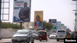 Motorists drive along a street with the campaign billboards of Somalia's Presidential candidates in Somalia's capital Mogadishu, Feb. 6, 2017.