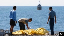 Beberapa anggota Basarnas memeriksa jenazah penumpang korban pesawat AirAsia (foto: dok). 92 korban tewas belum ditemukan di perairan Laut Jawa.